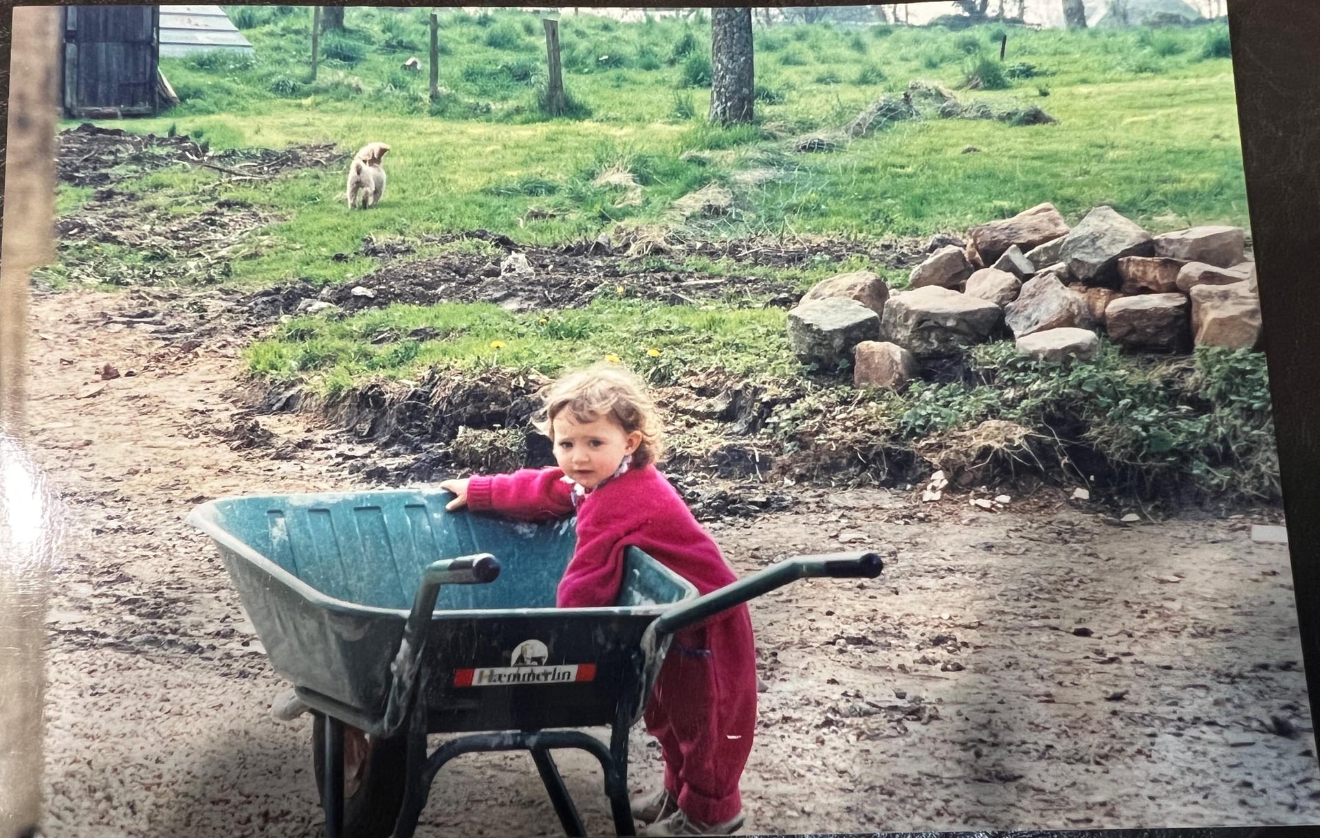 Emeline enfant, brouette à la main, dans la campagne familiale