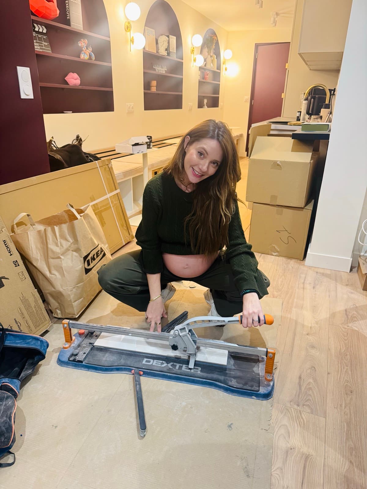 Emeline accroupie sur un chantier extérieur avec ses outils
